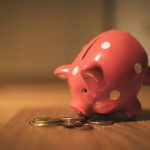 Hucha con monedas representando el ahorro necesario antes de empezar a invertir