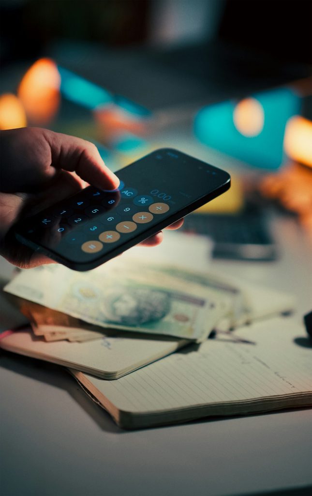 Persona usando la calculadora del móvil sobre billetes para revisar comisiones bancarias
