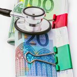 Estetoscopio sobre billetes de euro, representando el coste económico de una baja laboral